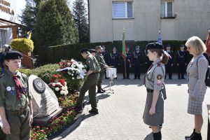 Przed pomnikiem stoją harcerze i Przedstawiciele Samorządu Powiatu Piaseczyńskiego przedstawiciel Powiatu Piaseczyńskiego