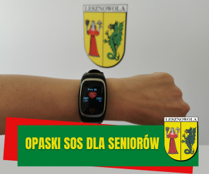 Na obrazu w centralnym miejscu widac przedramie z czarnym cyfrowym zegarkiem na nadgarstku. U góry i na dole po praej stronie herb gminy. Na zielonym pasku na dole napis: OPASKI SOS DLA SENIORÓW.