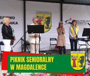 cztery osoby stją na scenie , na dole na zielonym pasku napois PIKNIK SENIORALNY W MAGDALENCE, po prawej herb gminy.