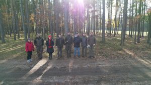 Las, osiem osób stoi na ścieżce i pozuje do zdjęcia