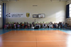 W tle dużo dzieci i osób dorosłych.