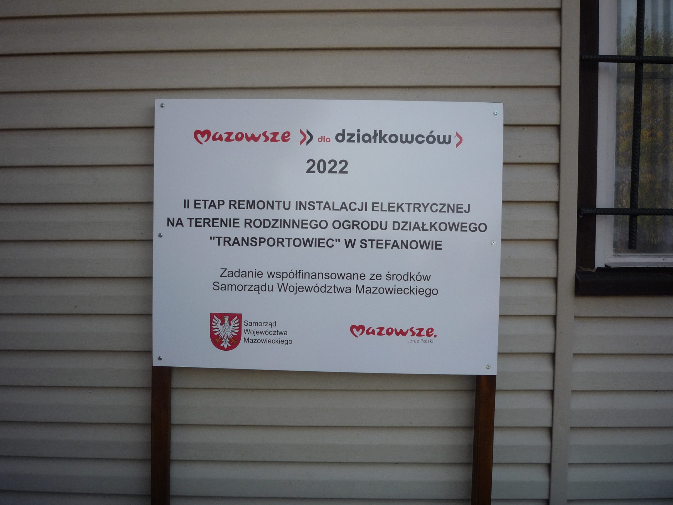 Zdjęcie tablicy informacyjnej dot.dofinansowania „II etap remontu instalacji elektrycznej na terenie Rodzinnego Ogrodu Działkowego ‘’Transportowiec’’ w Stefanowie”