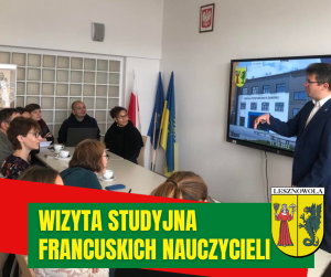 osoby siedzące przy stole, jedna stoi przed ekranem zawieszonym na ścianie. Na dole na zielonym pasku napis: WIZYTA STUDYJNA FRANCUSKICH NAUCZYCIELI, obok herb gminy.