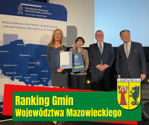 Cztery osoby stoją obok biało-granatowej planszy, na dole na zielonym pasku napis: RANKING GMIN WOJEWÓDZTWA MAZOWIECKIEGO, obok po prawej herb gminy.