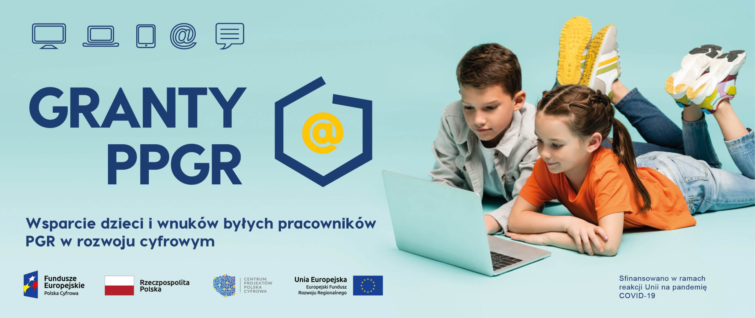 Dwoje dzieci leży na ziemi i korzysta z laptopa.