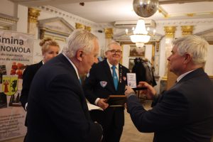 Trzech mężczyzn i kobieta podziwiają medal.