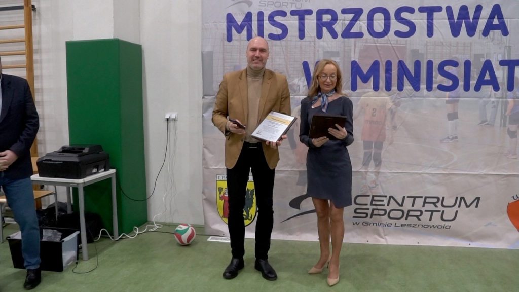 Minisiatkówka w hali Centrum Sportu w Mysiadle - kobieta i mężczyzna z dyplomami stoją w hali sportowej