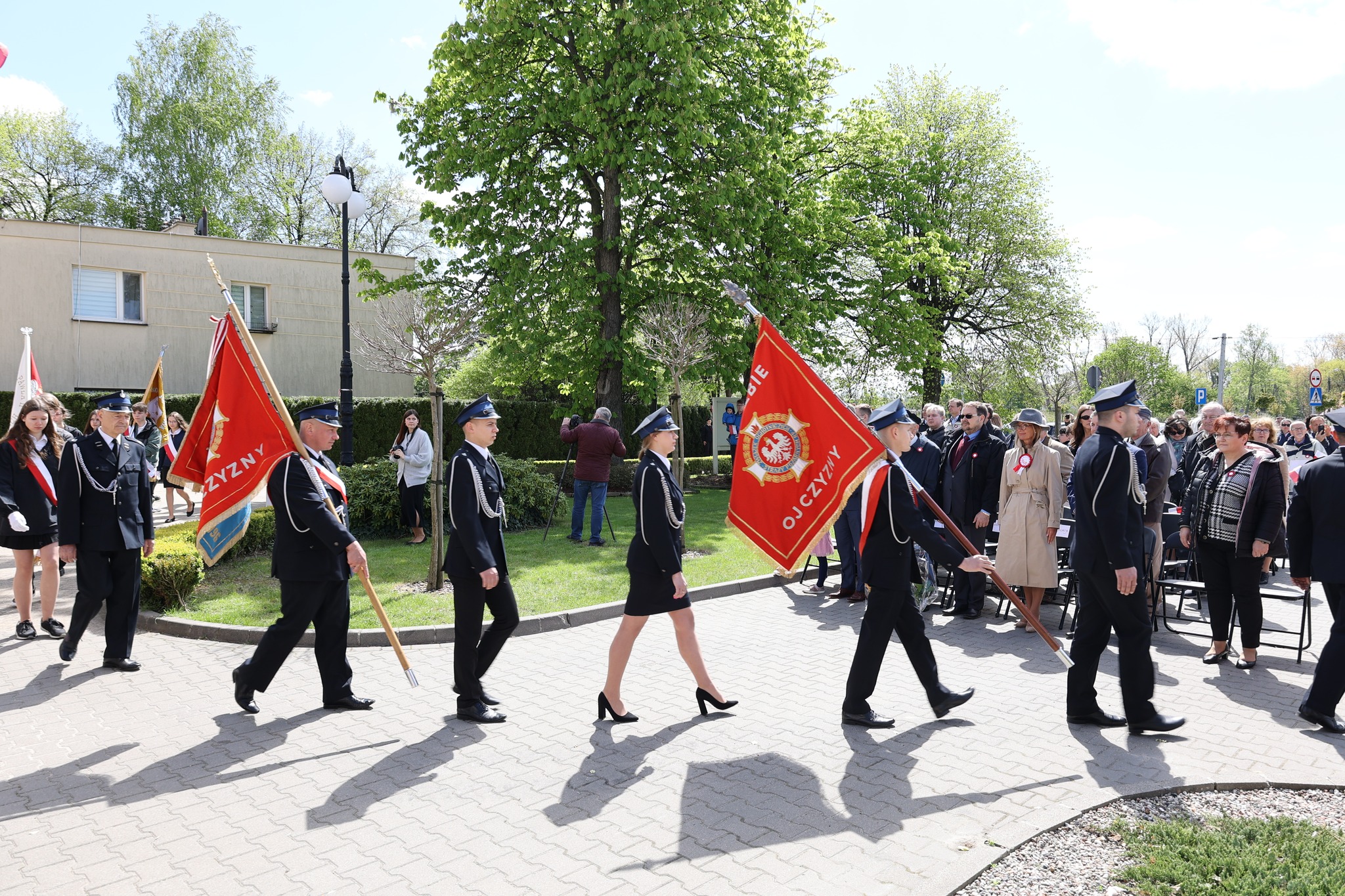 Strażacy i druhowie odmaszerowują ze sztandarami.