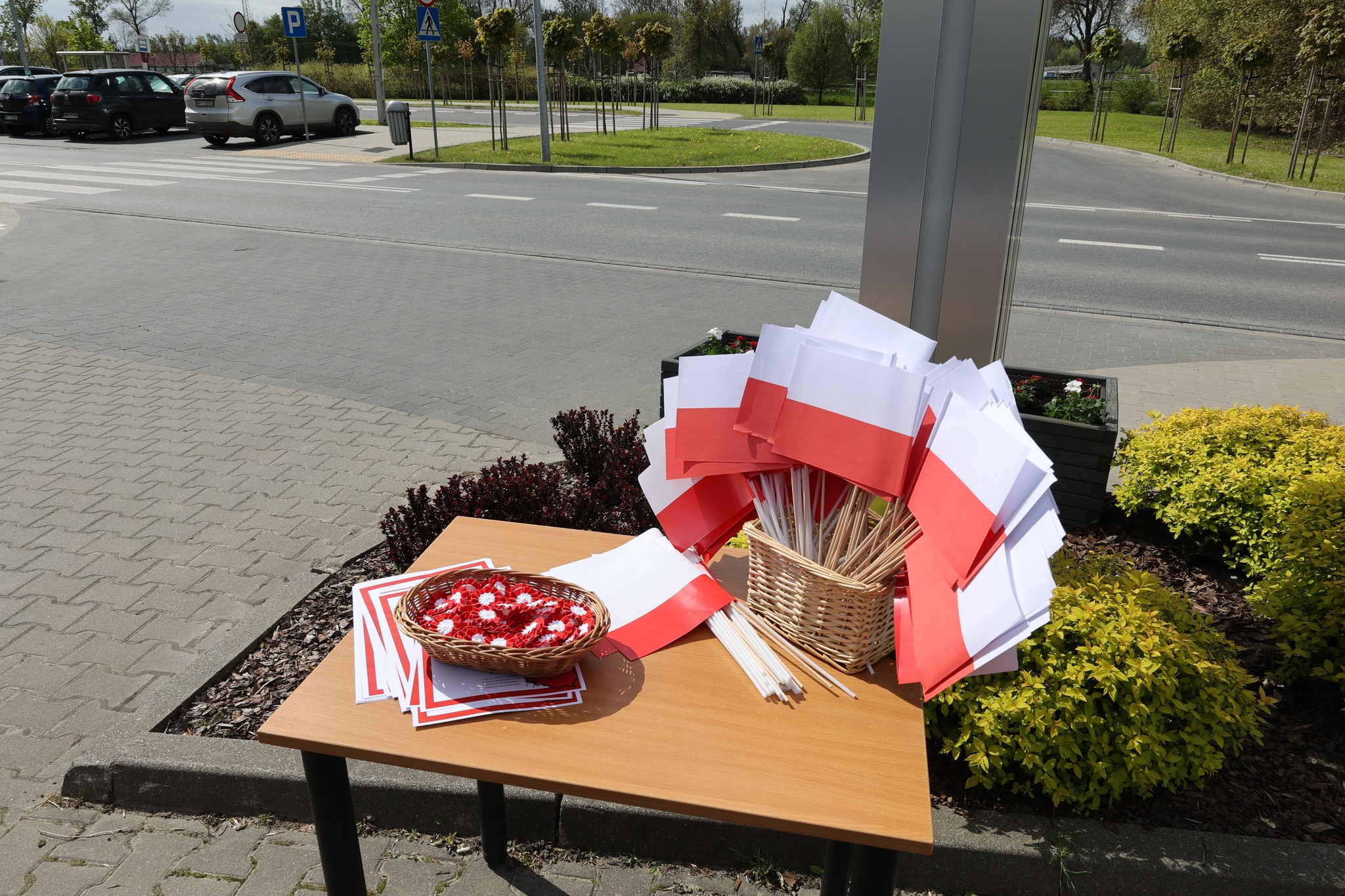 Flagi, kotyliony i śpiewniki na stoli przy wejściu na uroczystość.