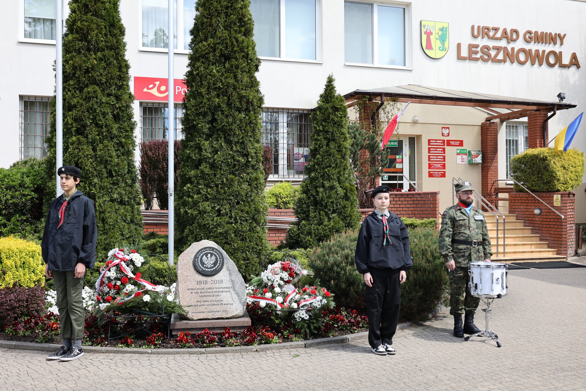 Druhowie stoją z werblistą przy pomniku przed Urzędem Gminy Lesznowola.