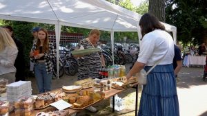 Kobieta stoi przy stoisku z ciastami i napojami.