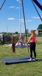 Dziecko huśta się na linie, a kobieta je asekuruje.