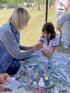 Kobieta maluje dziecku tatuaż na ręku.