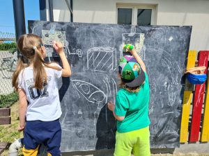 Chłopiec i dziewczynka rysują po tablicy.