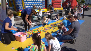 Dzieci układają klocki lego na kolorowych matach.