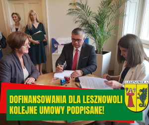 Osoby siedzące przy okrągłym stole w trakcie podpisywania umów.