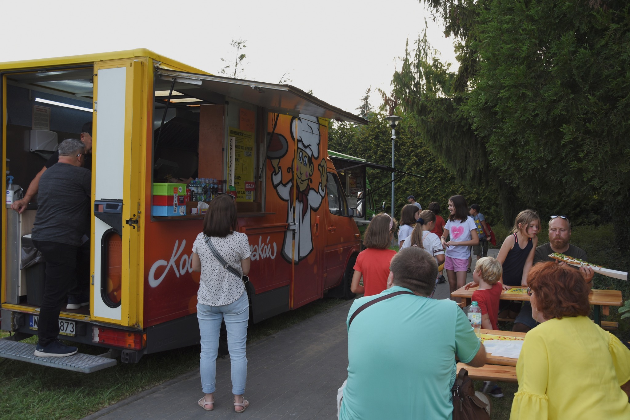 Foodtruk i i osoby siedzące przy stolikach.