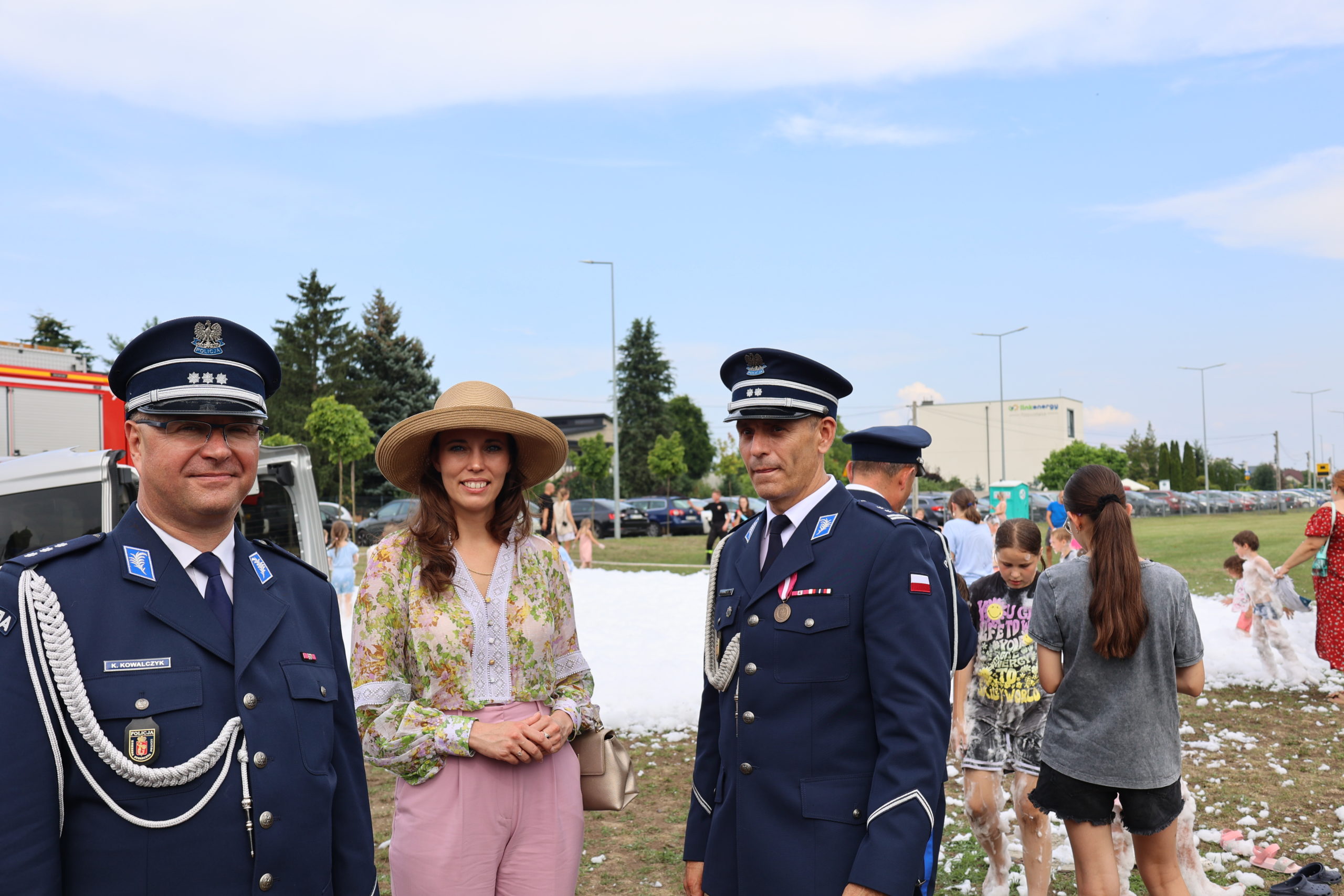 Dwóch policjantów i Wójt Gminy stoją przed miejscem, w którym jest piana strażacka dla dzieci