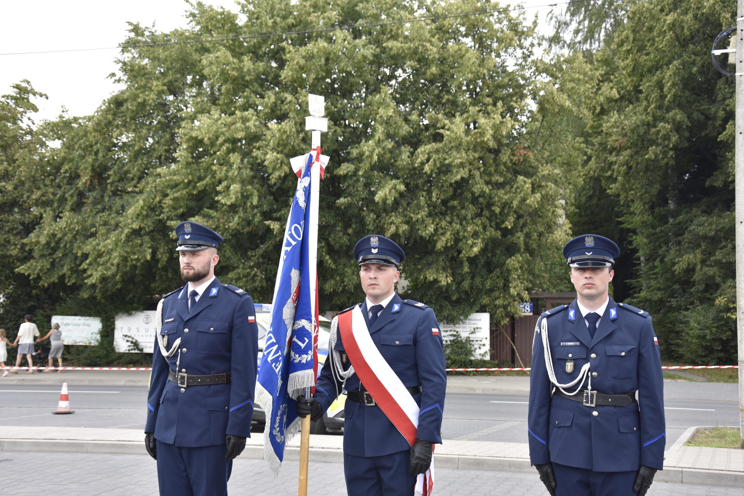 Trzech policjantów stoi ze sztandarem