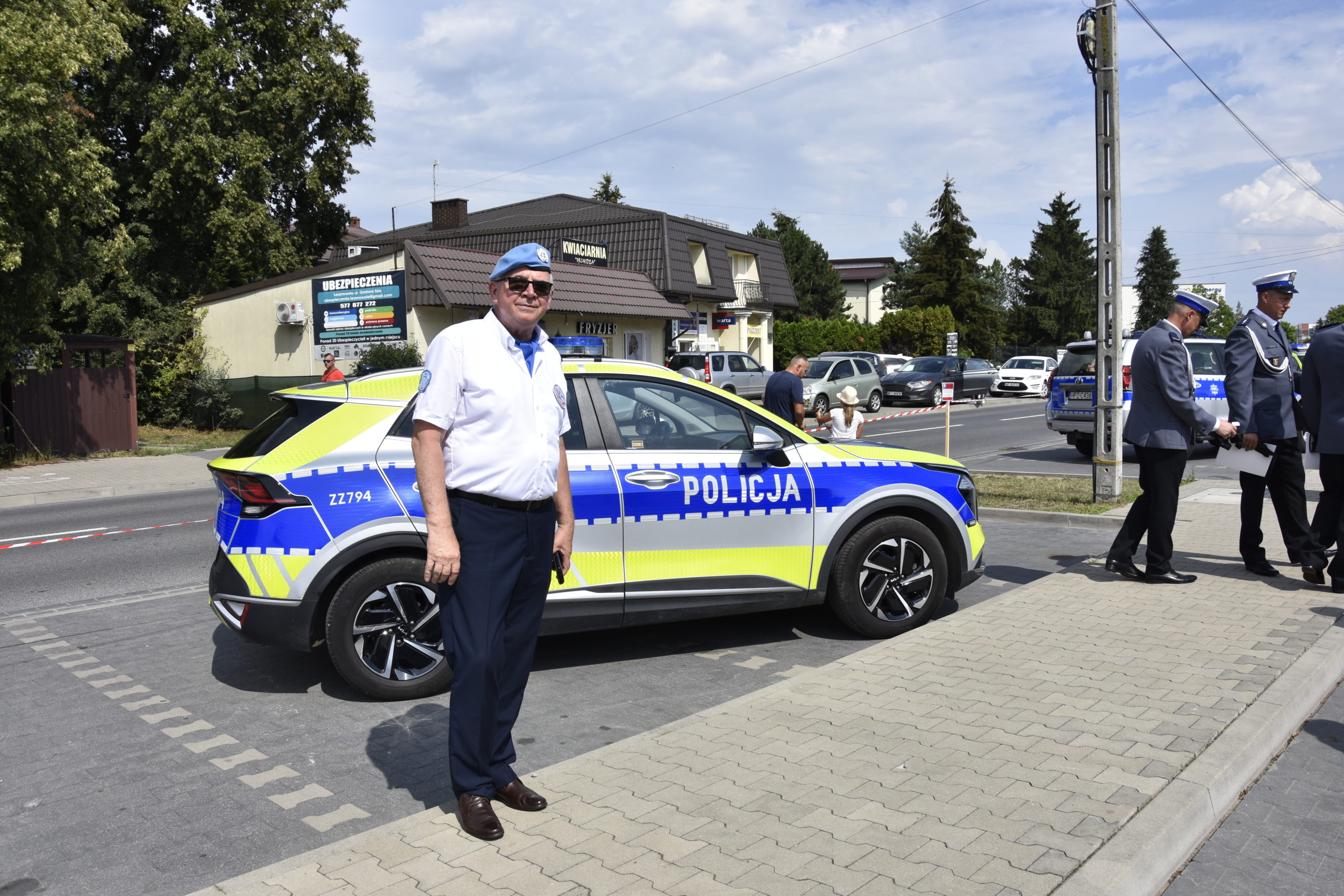 Mężczyzna w berecie żołnierza stoi przy policyjnym samochodzie
