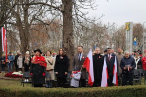 Stojąca grupa osób, niektóre osoby trzymają flagę.