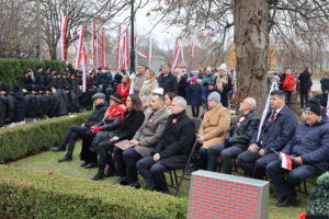 Siedząca grupa osób, w oddali widoczne zuchy