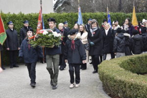Grupa osób oraz harcerze z wieńcem. Poczty sztandarowe