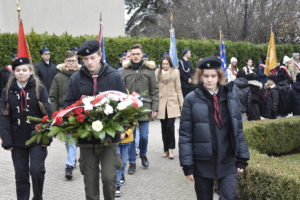Dwaj mężczyźni, kobieta oraz harcerze z wieńcem. Poczty sztandarowe