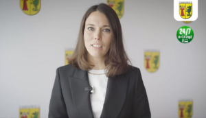 Na pierwszym planie postać kobiety - Wójt Gminy Lesznowola, po prawej u góry herb gminy oraz zielona grafika z napisem 24/7 , e-Urząd.