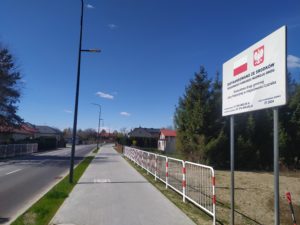 na obrazku widać chodnik, trawnik i ulicę