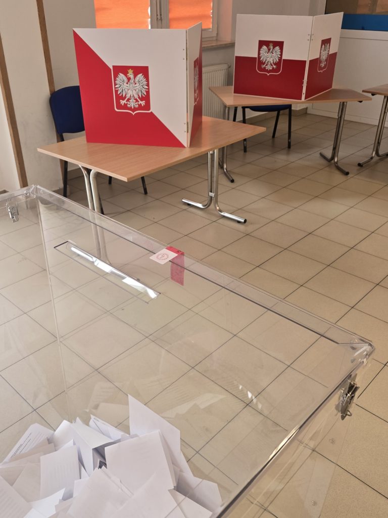 Na zdjęciu lokal wyborczy, widac stanowiska do głosowania i na pierwszym planie fragment urny wyborczej